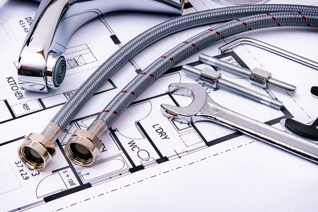 service-02 Close-up of plumbing tools and faucet on top of an architectural blueprint, perfect for hardware and construction themes.